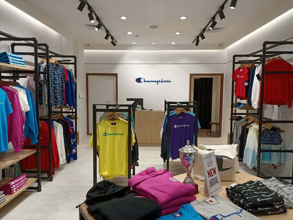「成為冠軍」 壁紙 — 光線明亮的Champion服裝店，展示著色彩繽紛的衣架和一個獎盃。