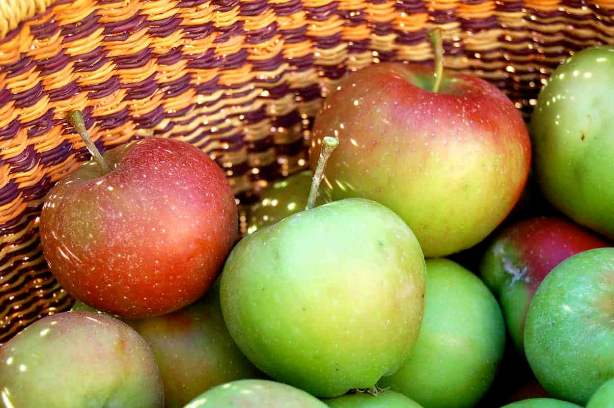 Fall Apples 桌布 壁紙 — 成熟的紅色和綠色蘋果在編織籃中閃耀著溫暖的金色光芒。