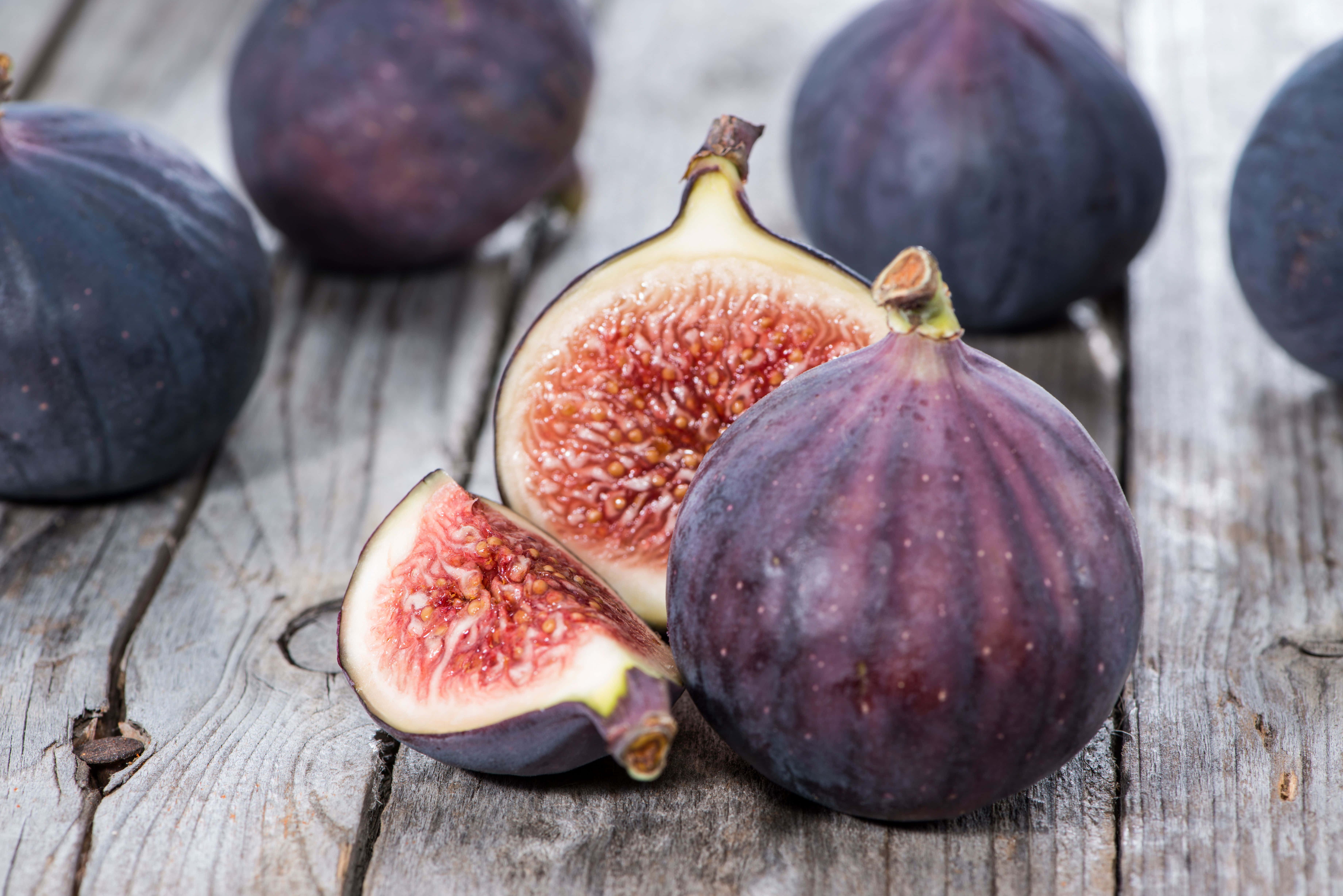 Purple Figs 桌布 壁紙 — 成熟的紫色無花果，內部呈粉紅色，放在經風化的木質表面上。