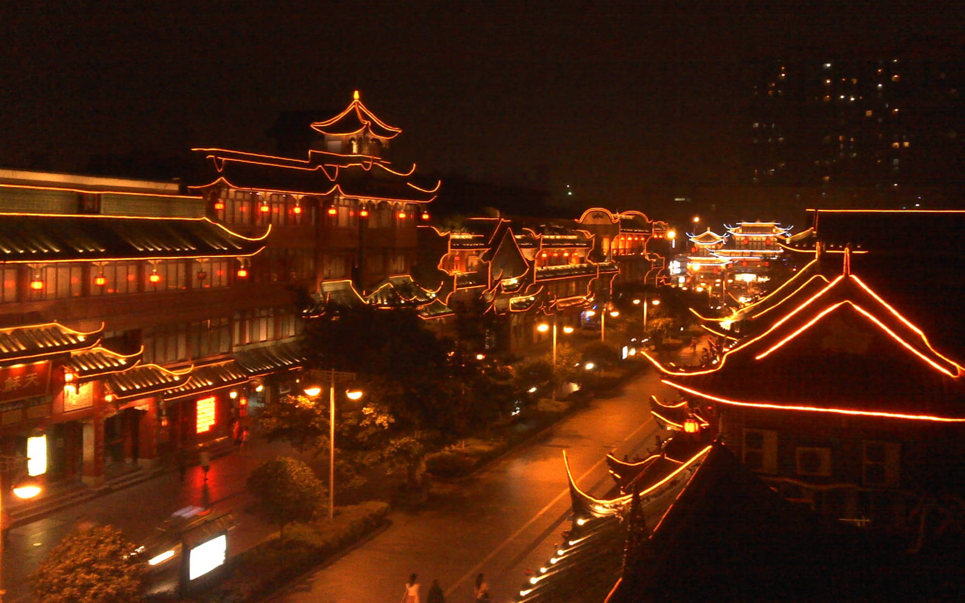 傳統中國建築在夜間沿著城市街道被橙色燈光照亮。