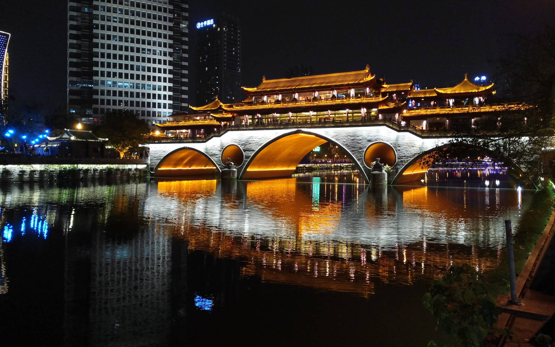夜晚河流上照明的傳統橋樑，城市燈光倒映在水中。
