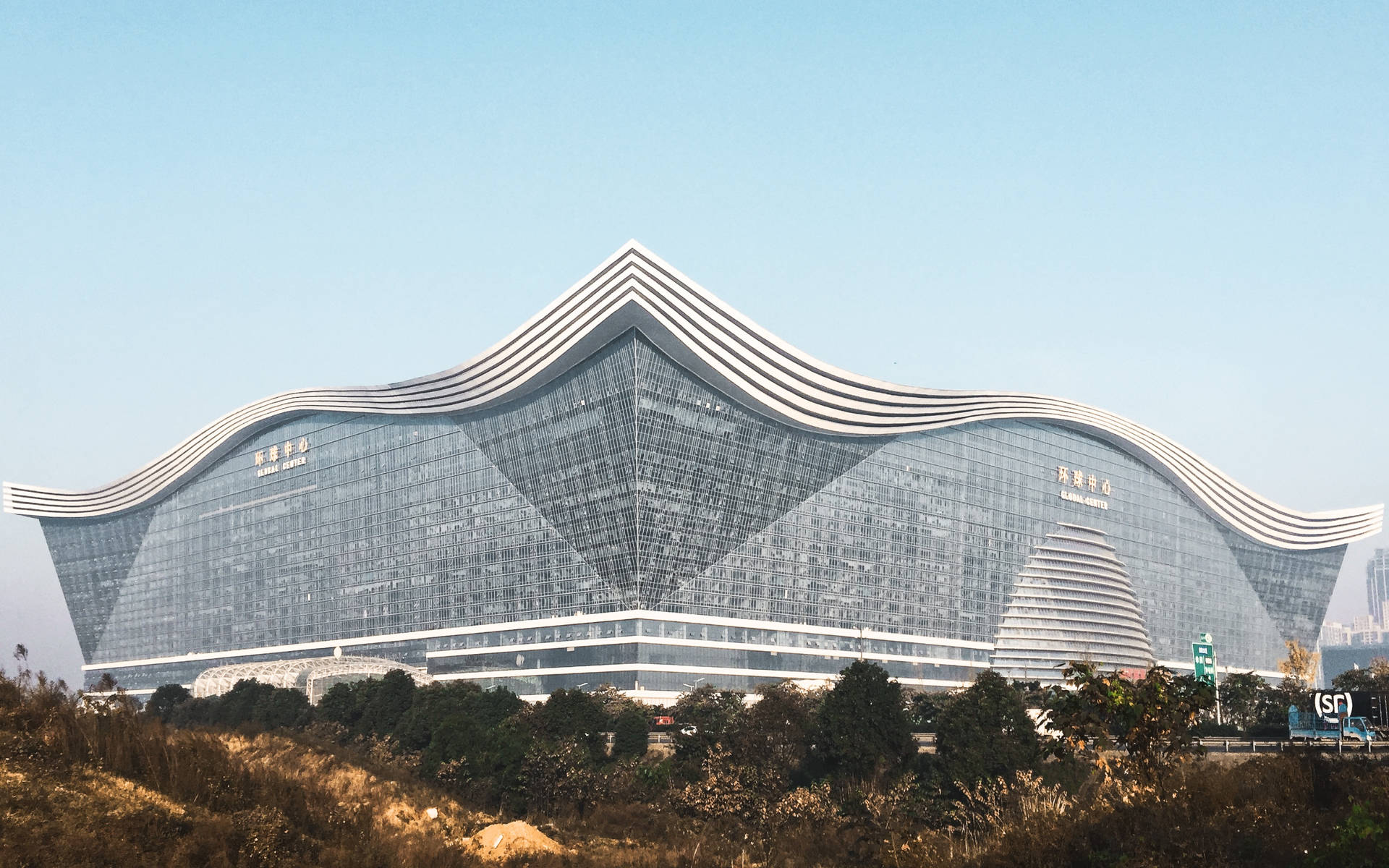 在清澈的藍天下，帶有波浪狀白色條紋的現代玻璃建築