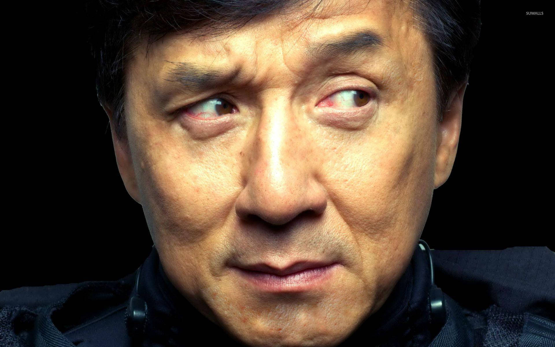 成龍投以懷疑神情 壁紙 — 成龍嘅特寫肖像，眼神銳利，眉頭緊鎖，背景係黑色。