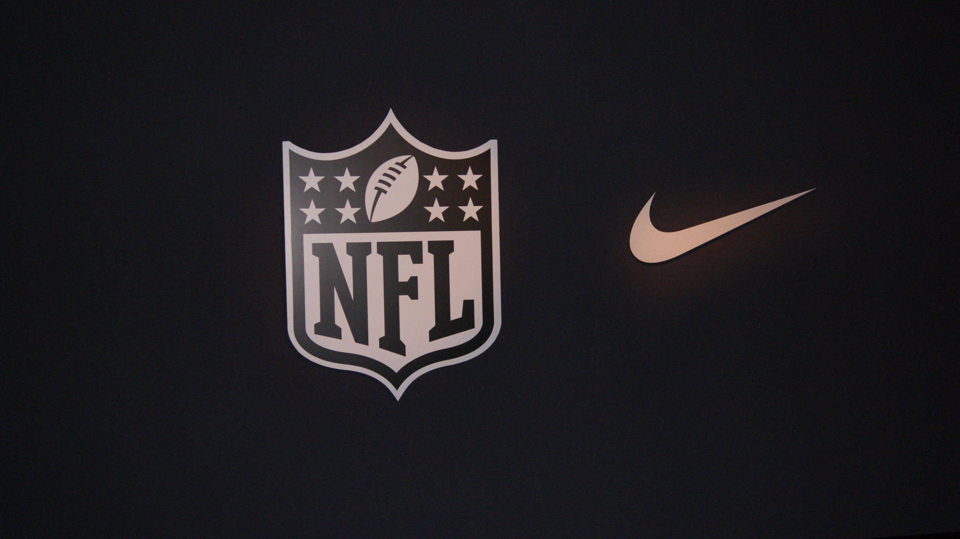 NFL 和 Nike 標誌在深色表面上發光。