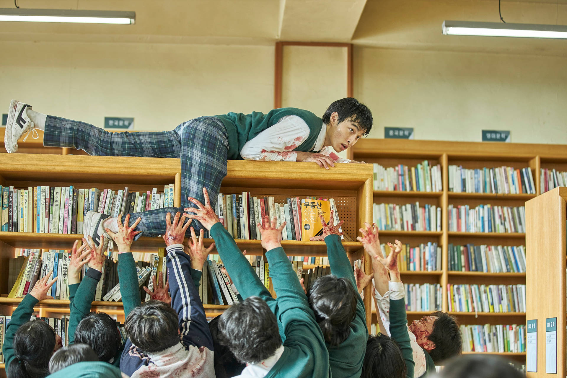 穿著校服的學生向圖書館書架上滿身鮮血的同學伸出沾滿鮮血的手。