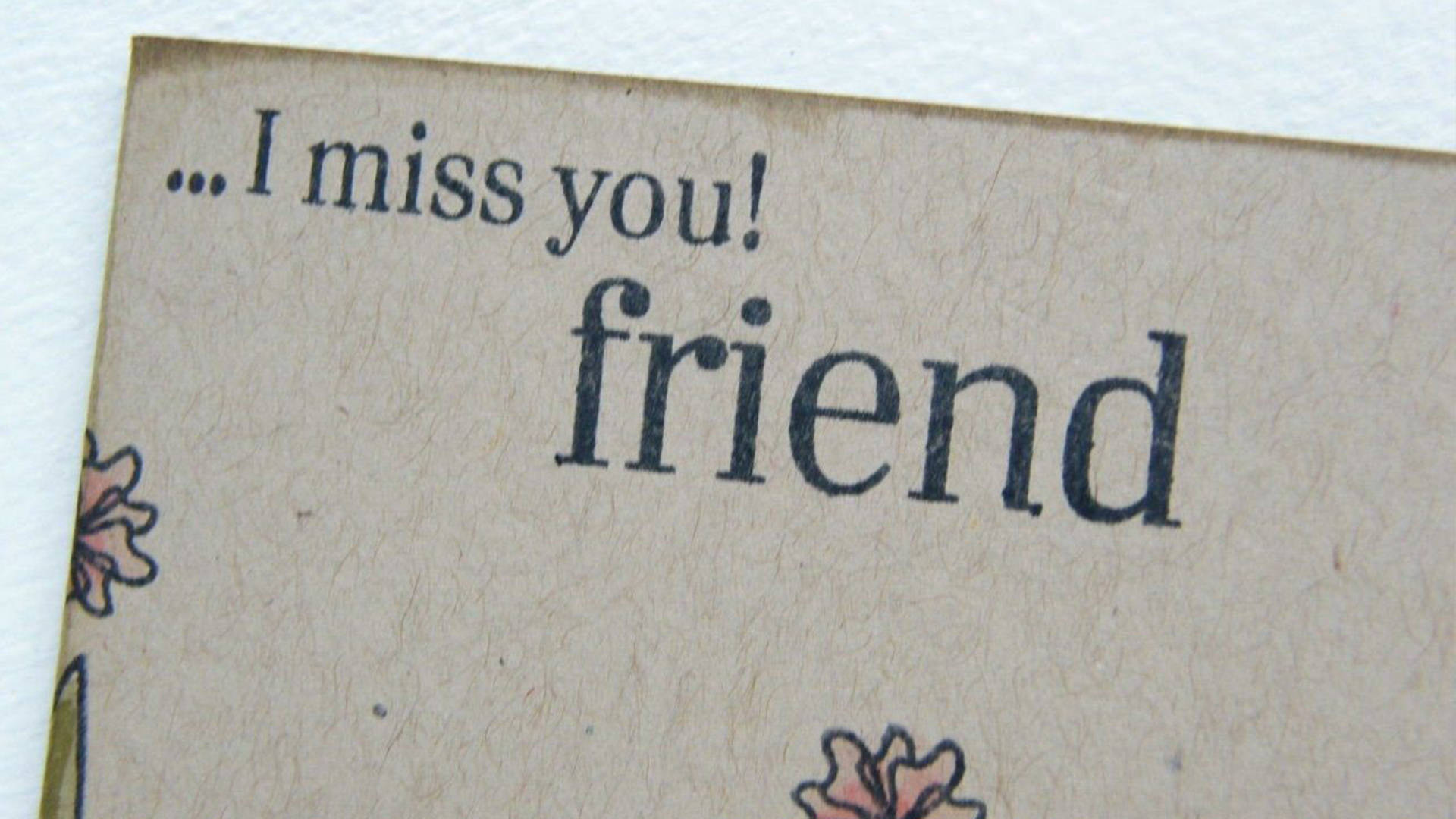 我好想你，朋友 壁紙 — 手工卡片的特寫，上面有文字 I miss you friend 和花卉塗鴉，採用有紋理的棕色紙張。