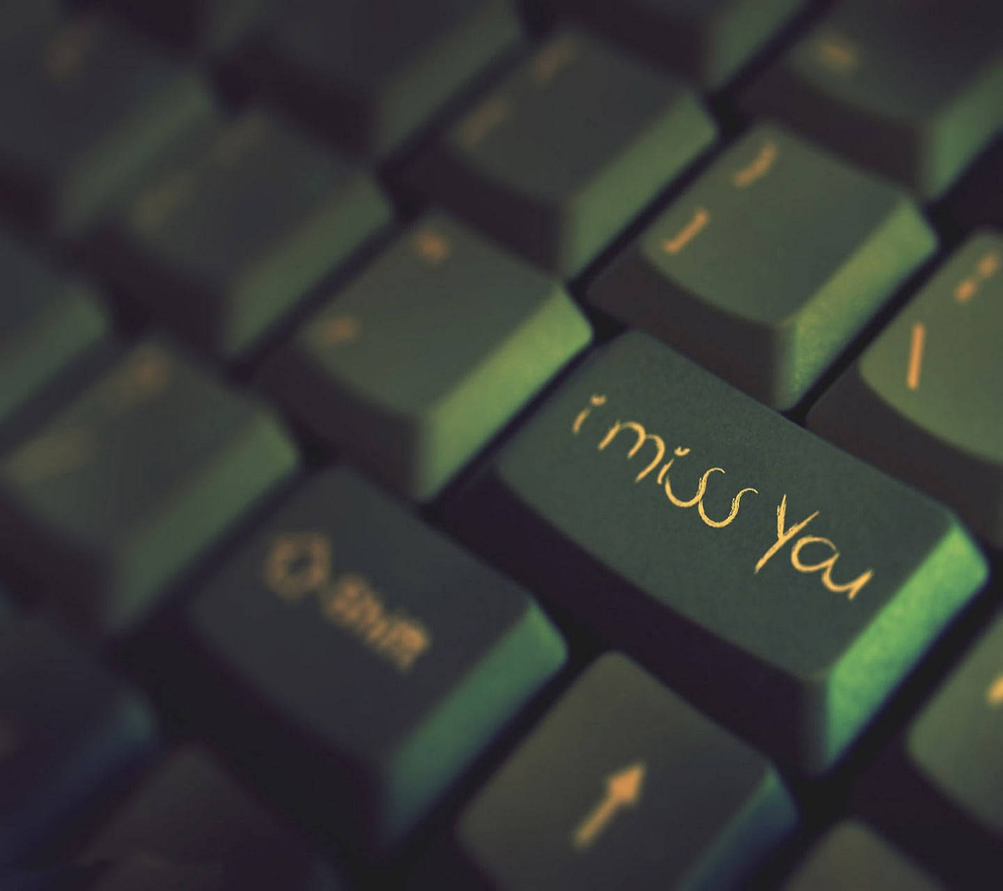 「我好想你」鍵帽 壁紙 — 深綠色鍵盤的特寫，自訂的「i miss you」按鍵在溫暖燈光下柔和發光。