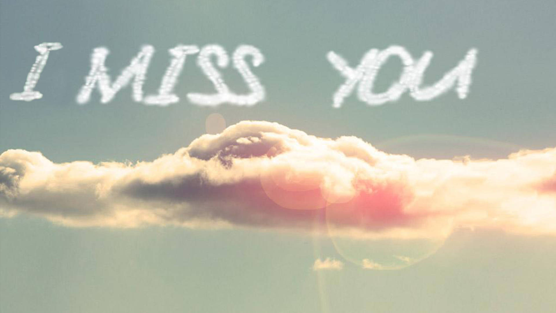 我好想你，陽光 壁紙 — 柔和的天空中，雲朵形成「I MISS YOU」的字樣，帶有溫暖的日落光芒和鏡頭光暈。