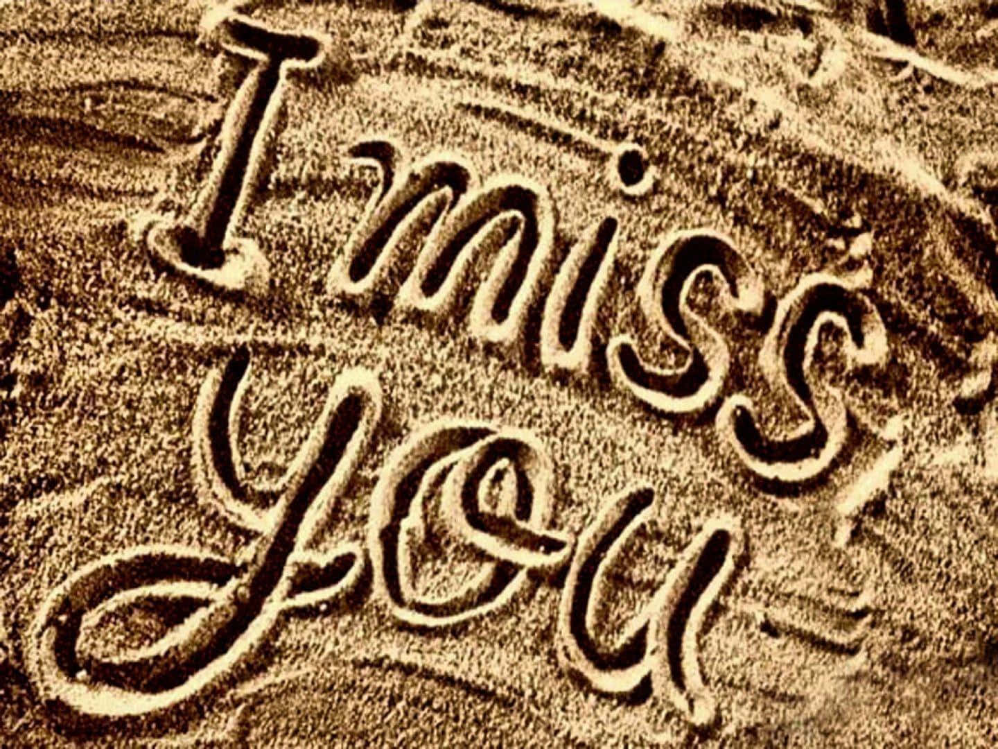 I Miss You 桌布 壁紙 — 「我想你」這幾個字以流暢的手寫體刻在帶有紋理的沙子上，呈現溫暖的懷舊色調。