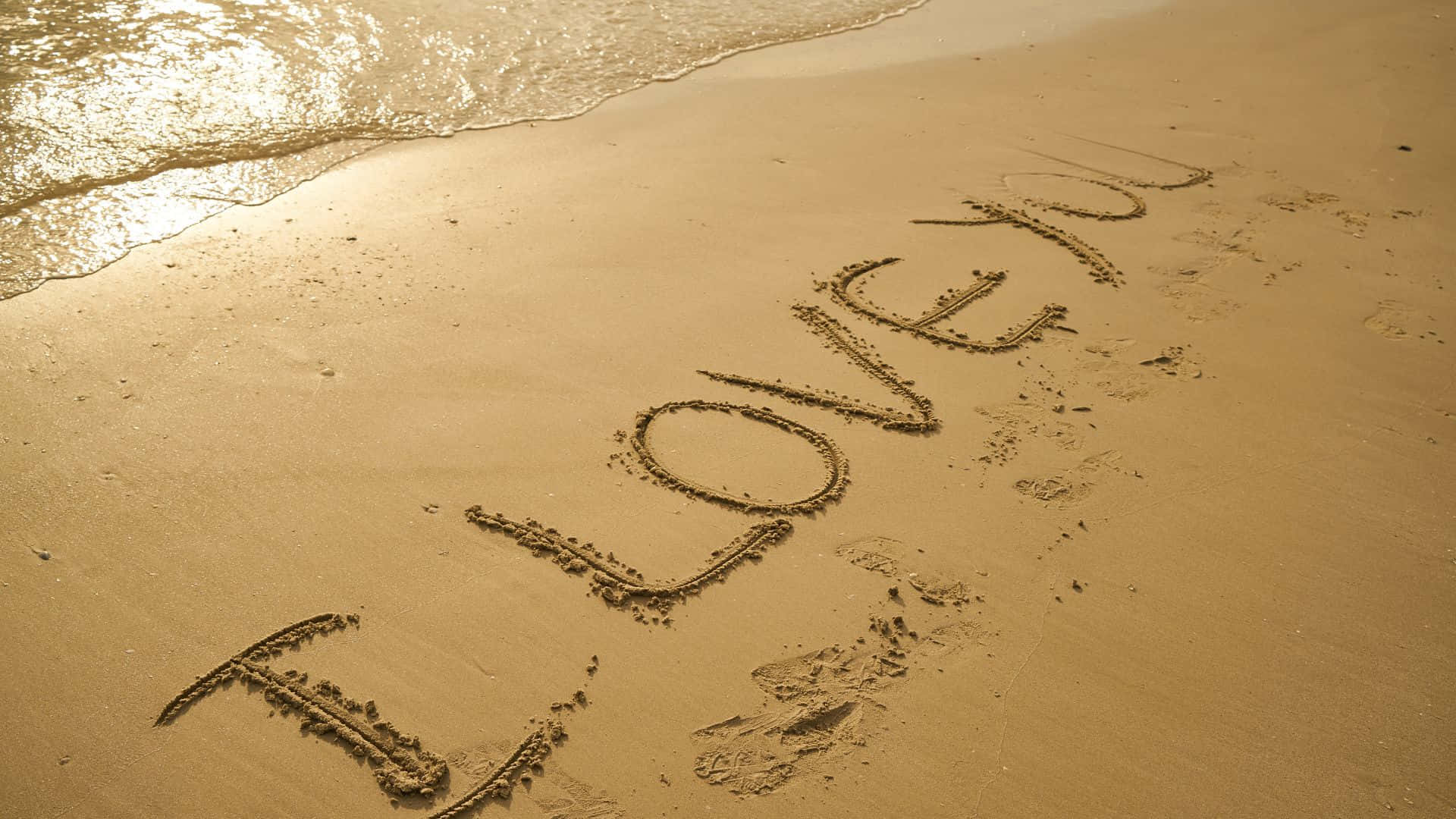 Beautiful Love 桌布 壁紙 — 「我愛你」這幾個字刻在濕沙上，溫柔的海浪在溫暖的金色光芒下拍打著海岸。