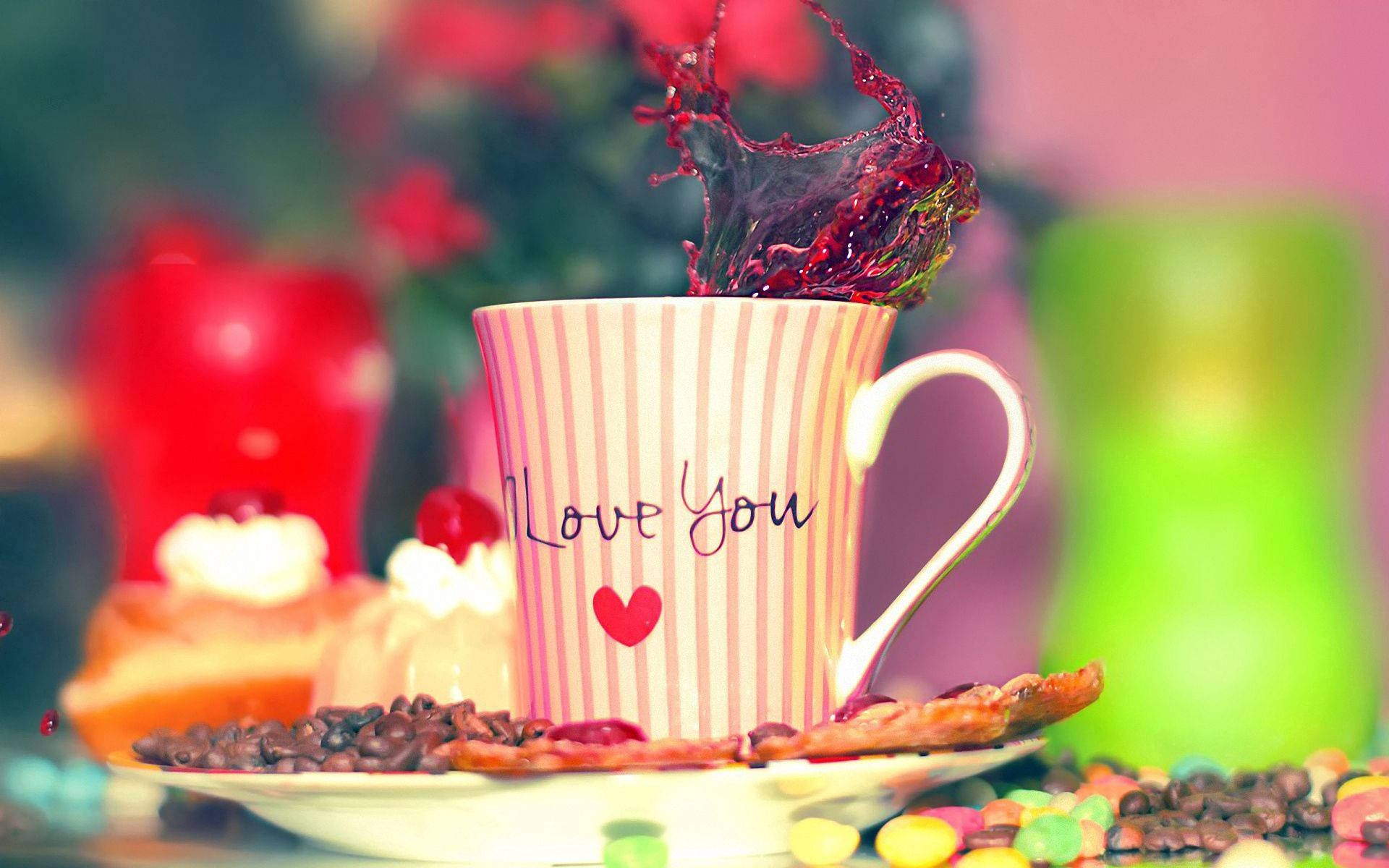 一個有「Love You」字樣的杯子，周圍有咖啡豆和糖果的紅色液體噴濺。