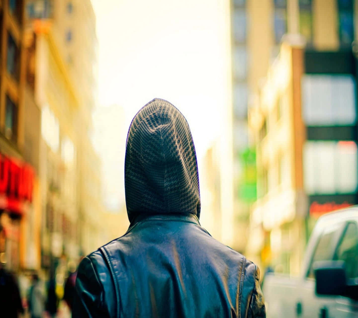 穿著連帽外套的人於黃金時刻沿城市街道走遠。
