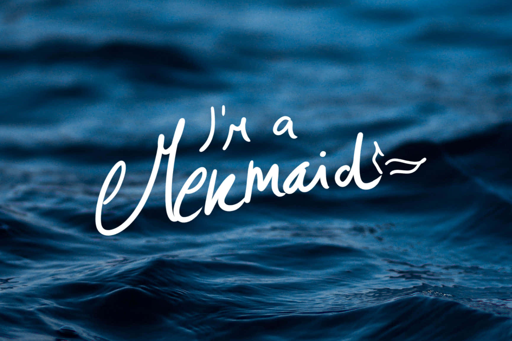 我是美人魚字體 壁紙 — 白色草書文字「I'm a Mermaid」漂浮在帶有紋理的深藍色海浪上。