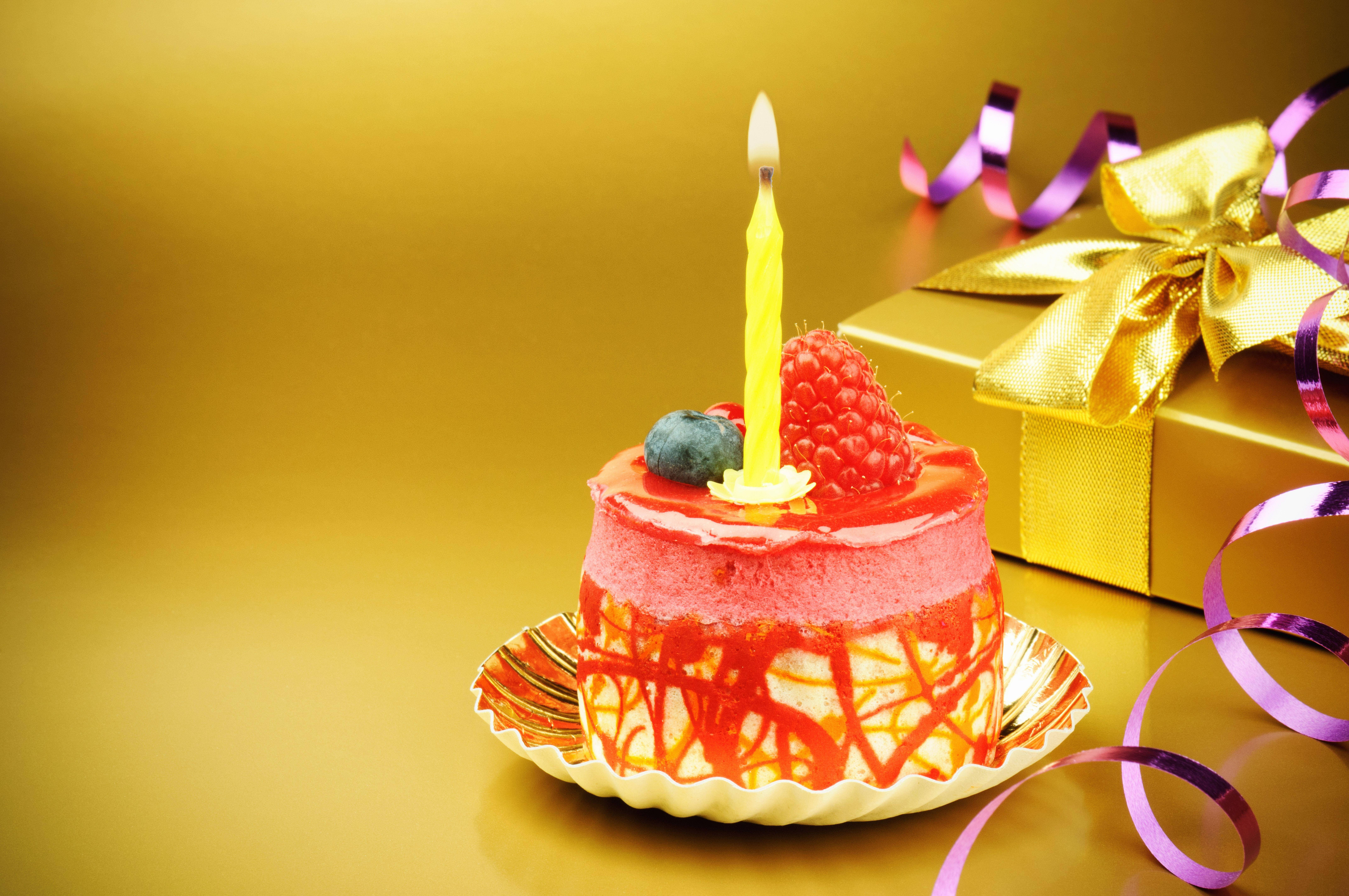 我的生日莓果蛋糕 壁紙 — 一個充滿活力的粉紅色生日蛋糕，上面有燃燒的黃色蠟燭和新鮮漿果，旁邊是一個金色禮物盒，裝飾著紫色絲帶。