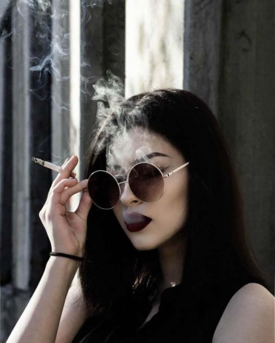 戴太陽眼鏡的女性在窗邊陽光下抽煙。