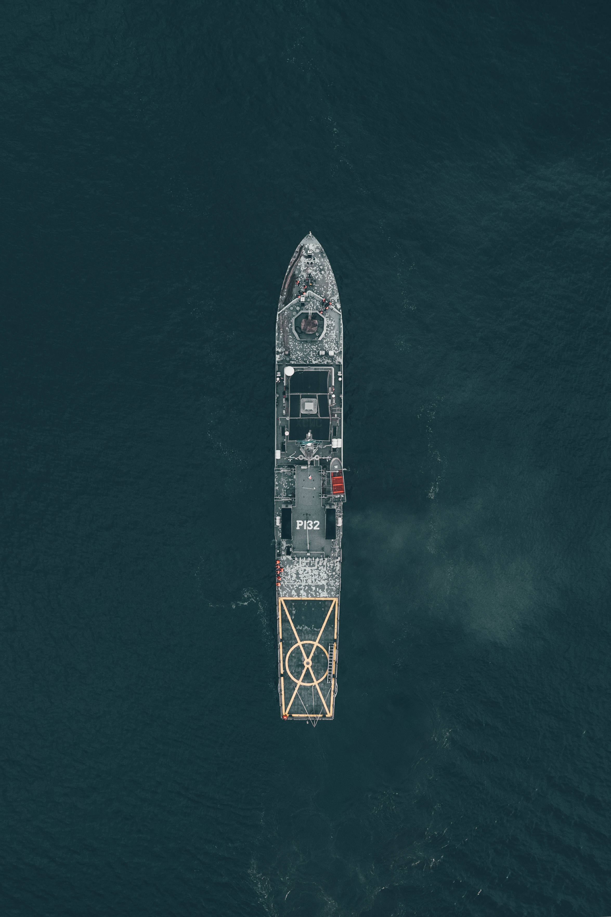 戰艦俯瞰圖 壁紙 — 標記為P132的軍用船隻在深藍綠色海洋中獨自航行的鳥瞰圖。