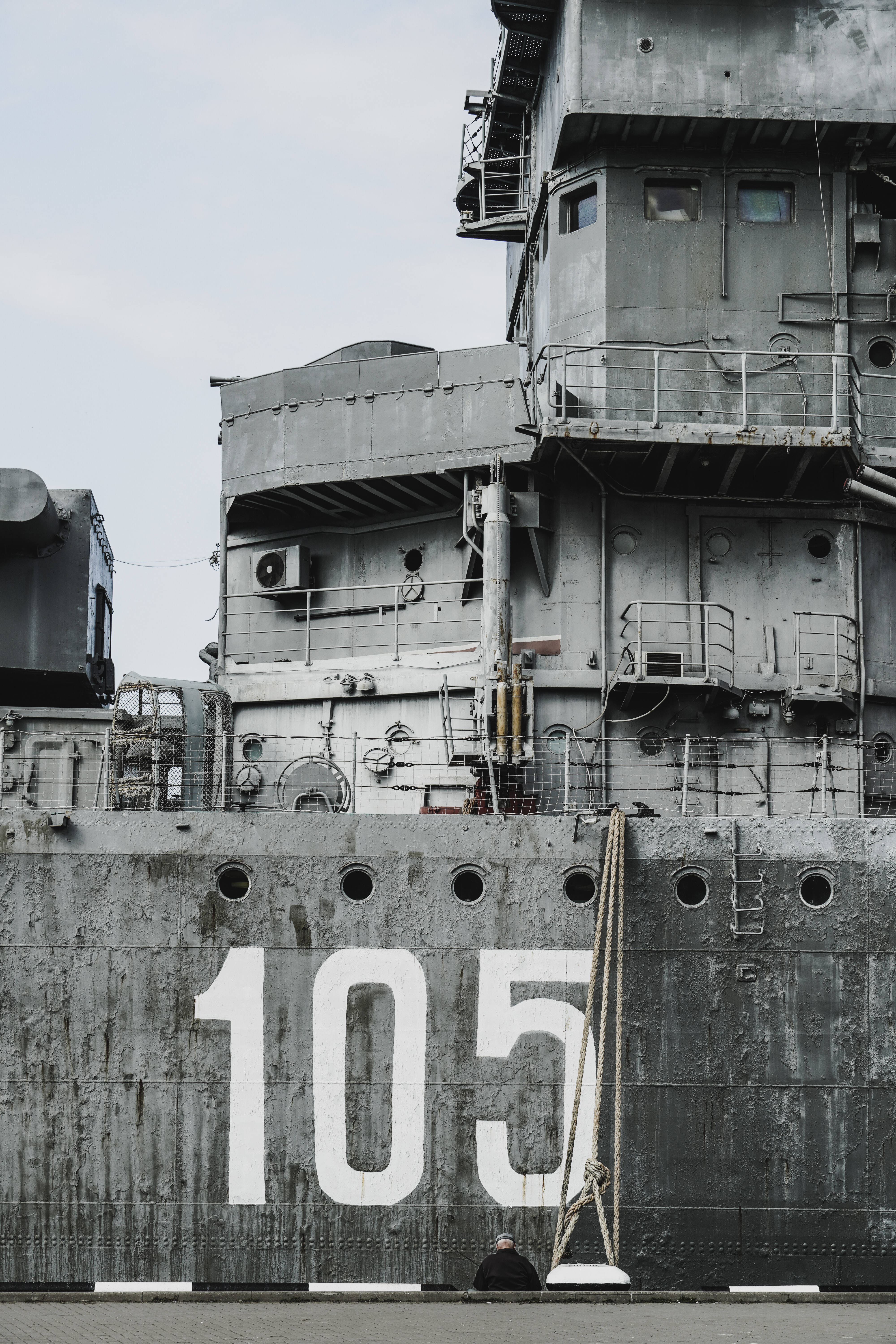 戰艦單色灰調 壁紙 — 一艘飽經風霜的軍艦，上面用粗體白色數字105，在陰天天空下佔據了畫面主導地位。