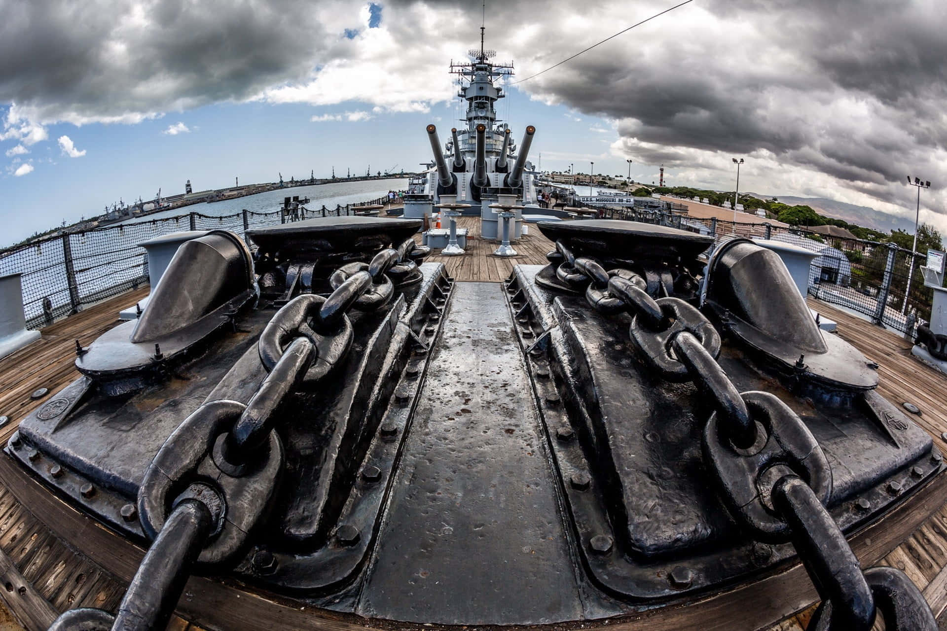戰艦的毀滅力量 壁紙 — 從戰艦甲板拍攝的戲劇性魚眼視角，顯示巨大的錨鏈在暴風雨的天空下通向高聳的炮塔。