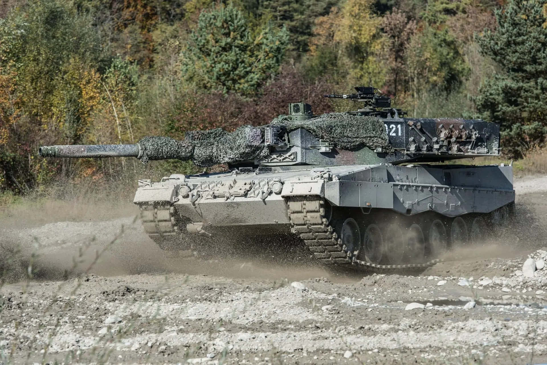 軍用坦克在秋日森林的泥土路上行駛