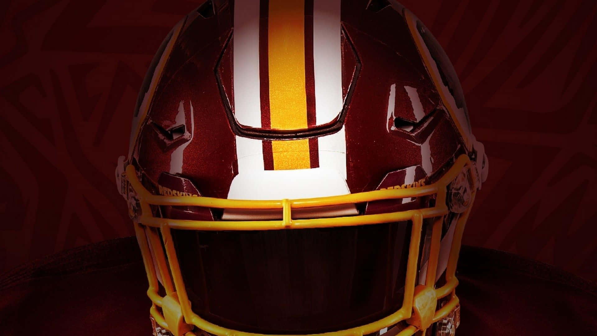 Washington Football 桌布 壁紙 — 戲劇性燈光下，一個亮面栗色美式足球頭盔的特寫，帶有醒目的黃色和白色條紋。