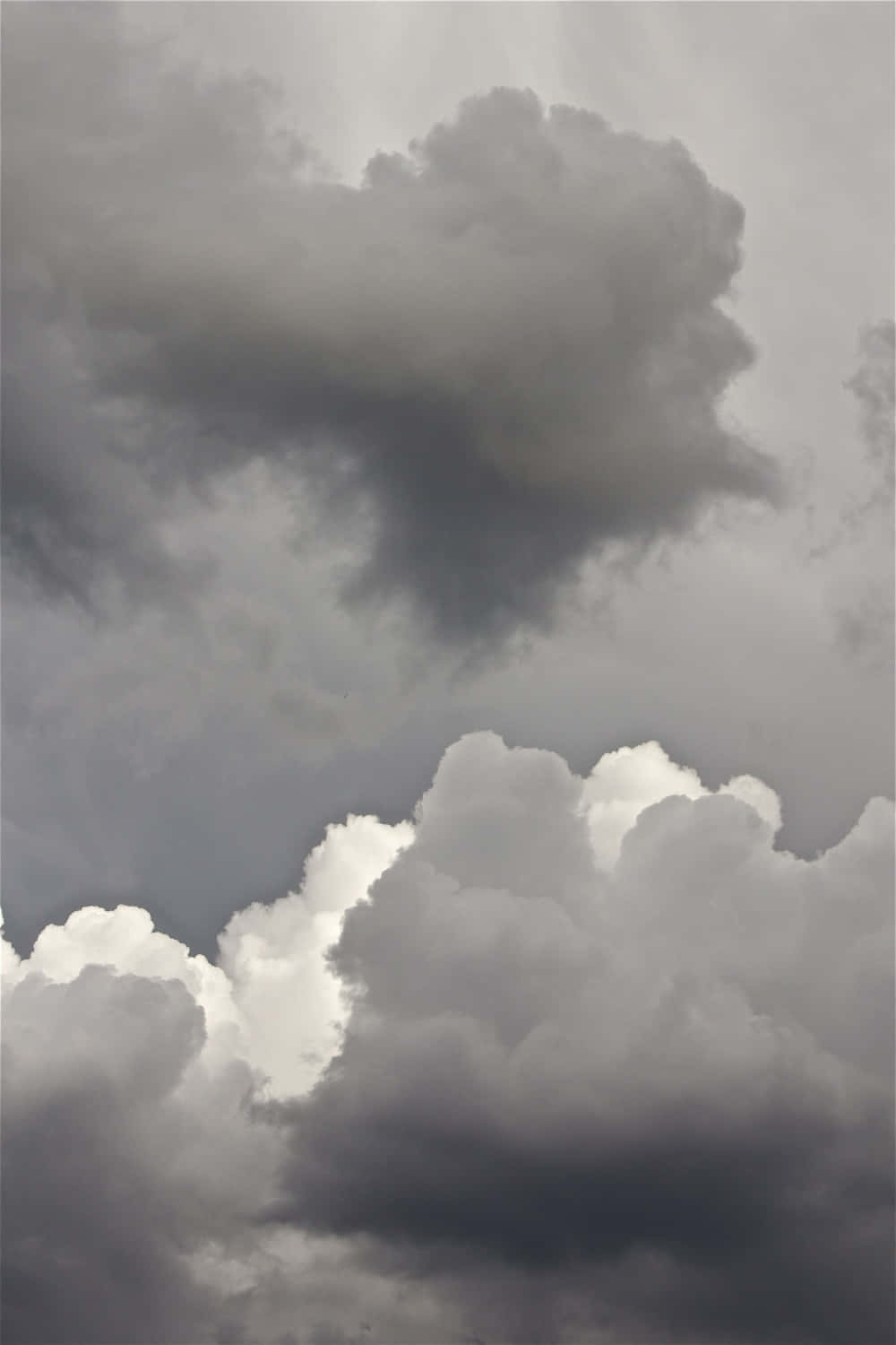 灰色 桌布 壁紙 — 戲劇性的單色雲層，深色暴風雨雲團與明亮蓬鬆的雲層形成對比。