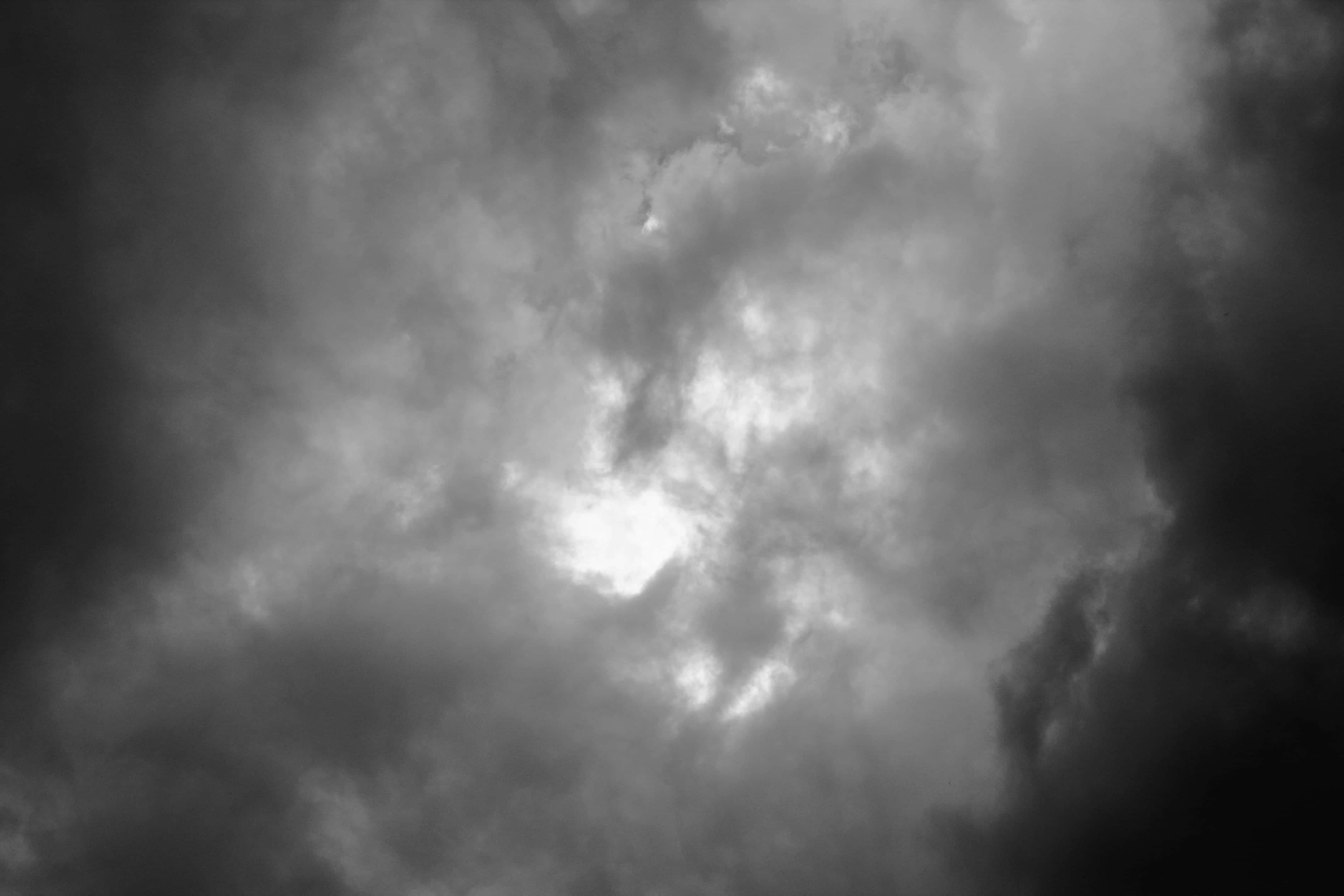 Dark Heaven 桌布 壁紙 — 戲劇性的單色雲層以強烈對比旋轉，明亮光線穿透黑暗的風暴結構。