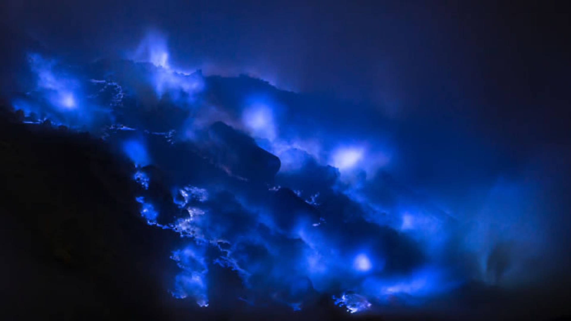Flames 桌布 壁紙 — 戲劇性的夜晚場景，發光的藍色生物發光波浪拍打著深色火山岩。