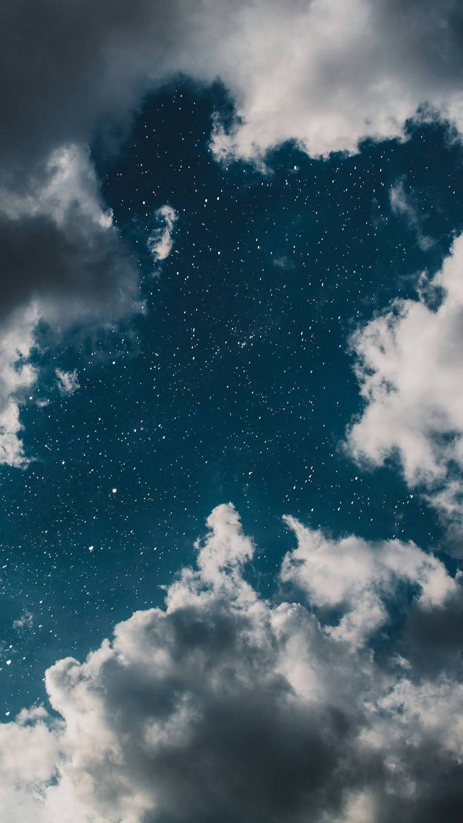 藍天 桌布 壁紙 — 戲劇性的夜空，蓬鬆的白雲框住深邃的藍色蒼穹，點綴著閃爍的星星。