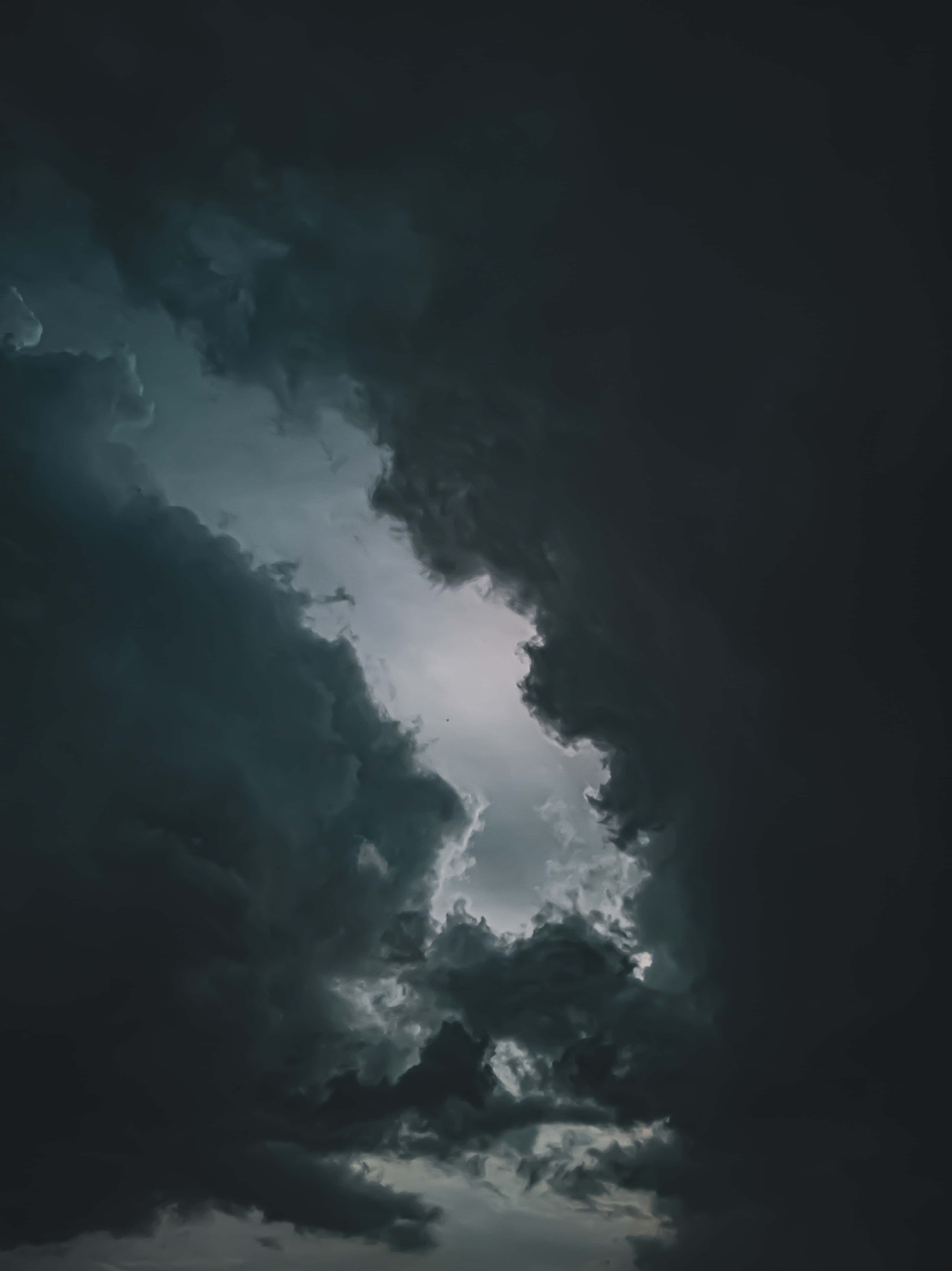 Dark Heaven 桌布 壁紙 — 戲劇性的天空，黑暗的暴風雲散開，露出上方明亮的發光開口。