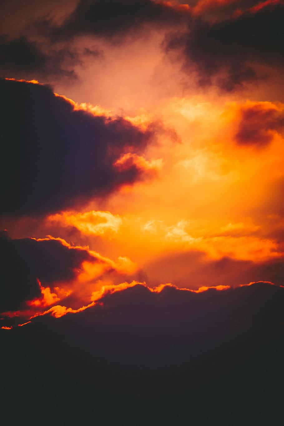 Orange Sunset 桌布 壁紙 — 戲劇性的日落雲彩在黑暗的天空中發出火橙色和深紫色的光芒。