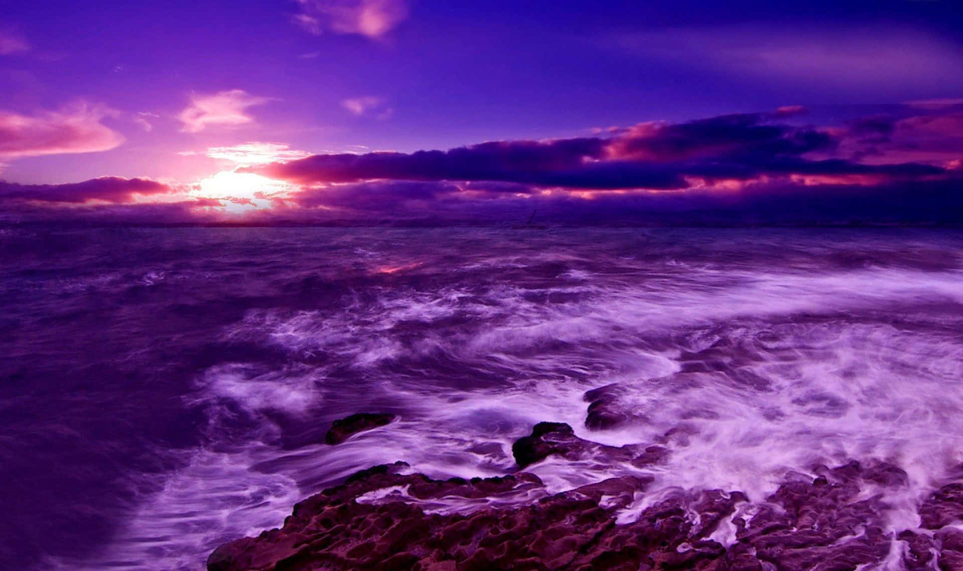Purple Sunset 桌布 壁紙 — 戲劇性的紫色日落，波濤洶湧的海洋，海浪拍打著黑暗的岩石。