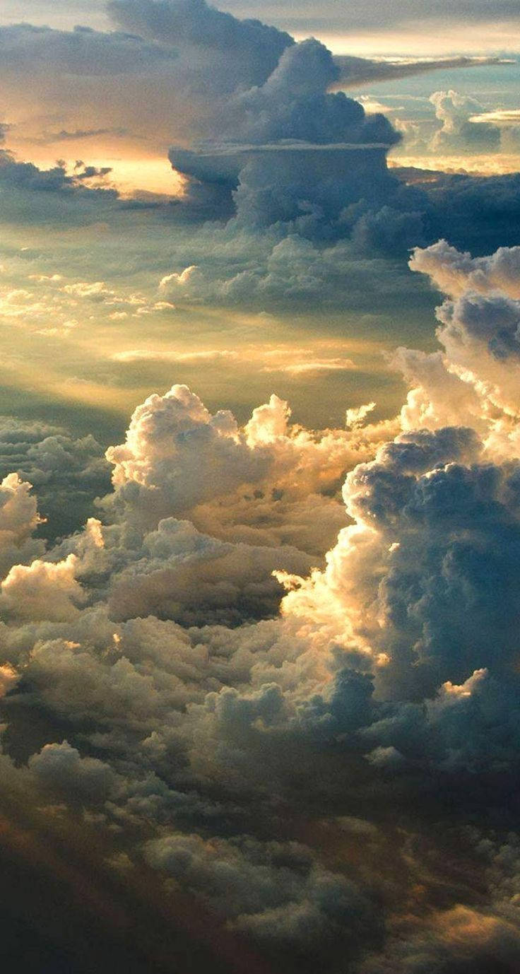 廣闊的雲層沐浴在金色夕陽光中，帶有深邃陰影和柔和亮點。 — 日落天空 壁紙