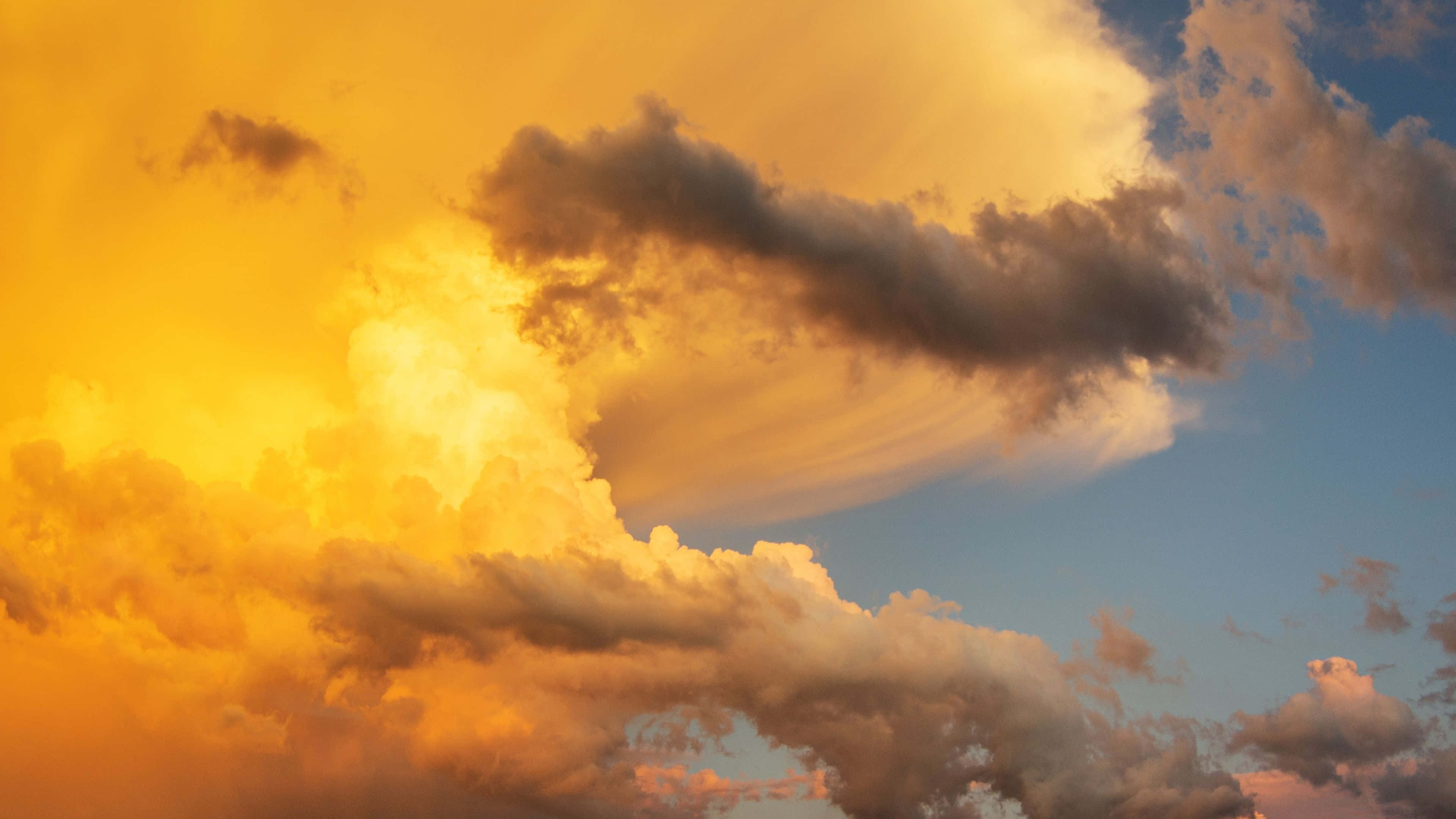 唯美雲朵動態 桌布 壁紙 — 戲劇性的雲彩在夕陽西下時散發出火熱的橙色和柔和的藍色光芒。
