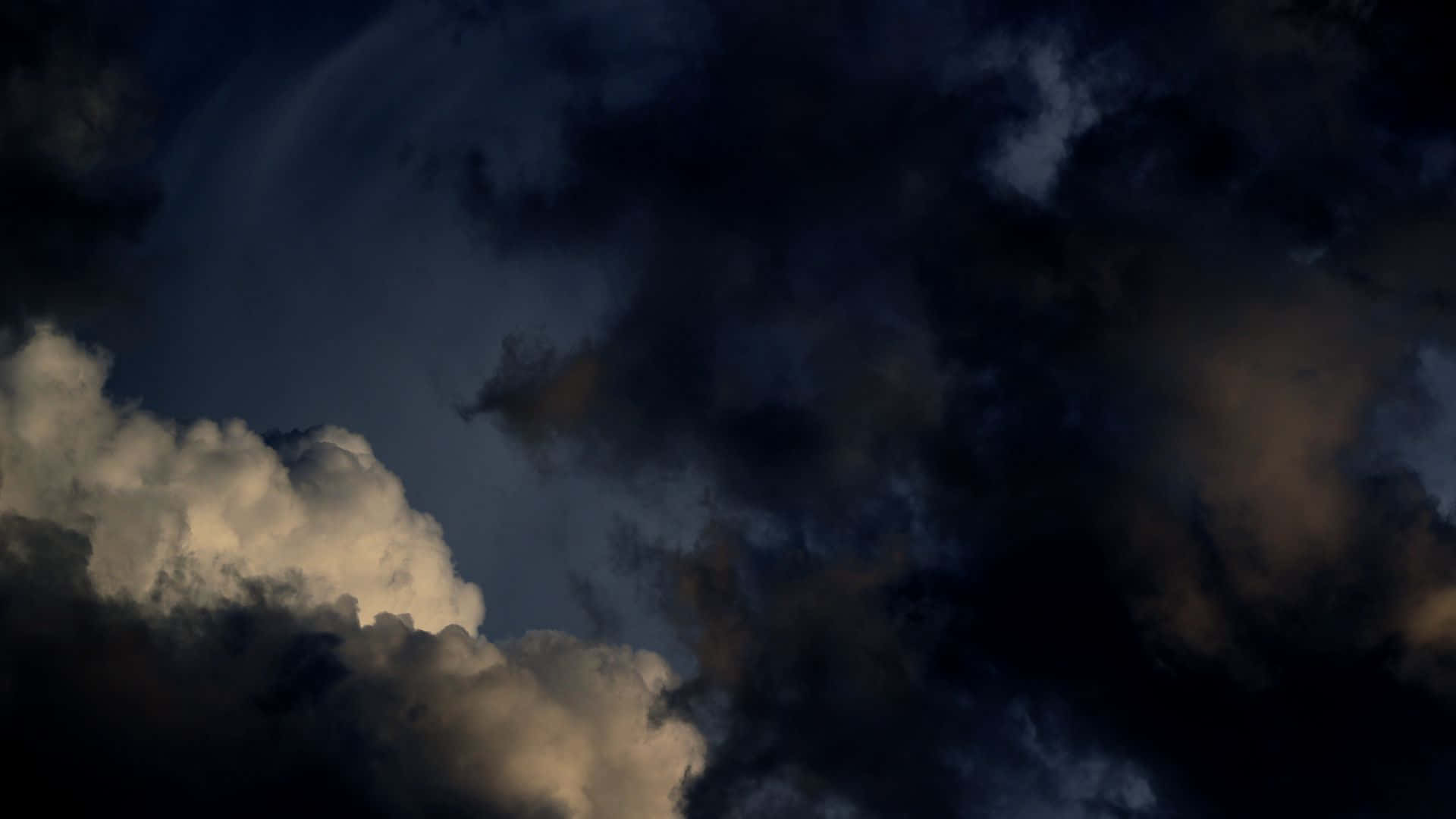 Ambience 桌布 壁紙 — 戲劇性的風暴雲在深藍色和灰色中旋轉，帶有金色亮點，襯托著黑暗的天空。