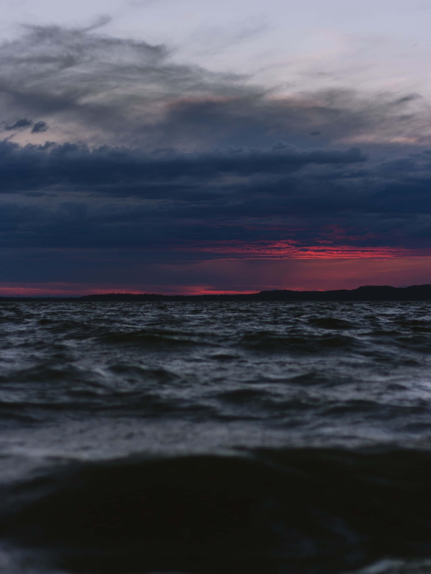 Black Sea 桌布 壁紙 — 戲劇性的黃昏海景，深色波浪在燃燒般的紅色和深紫色雲彩的天空下翻騰。