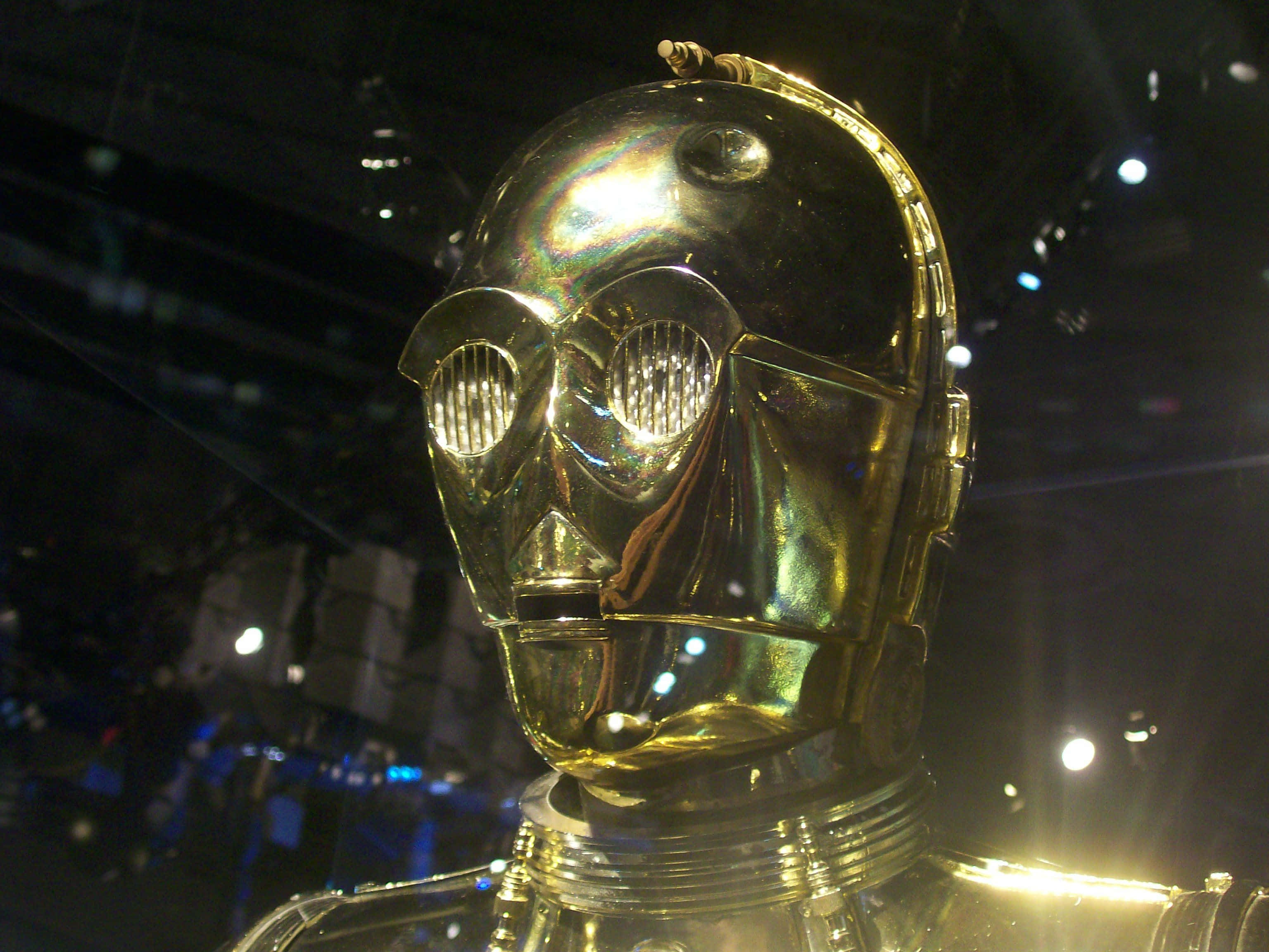 C-3po 桌布 壁紙 — 戲劇性舞台燈光下，閃亮金色機械人頭部特寫，眼睛發光。
