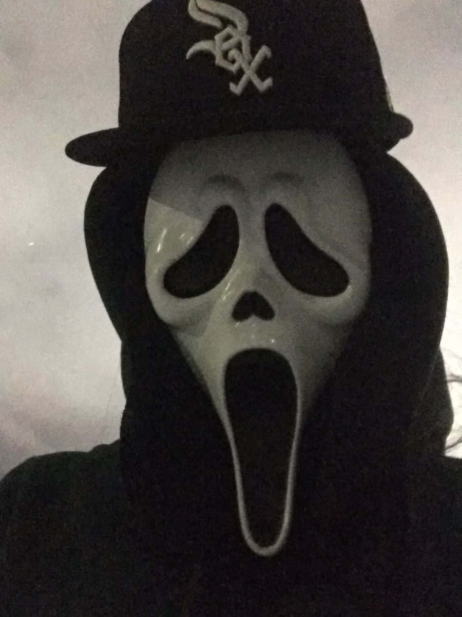 戴著 Ghostface 面具、身穿黑色連帽衫和棒球帽的人。
