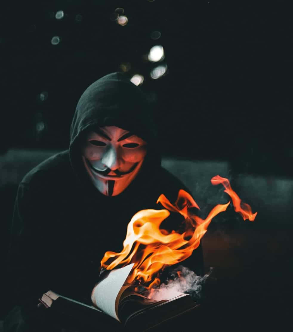 戴著蓋伊·福克斯面具的人晚上看著書燃燒。