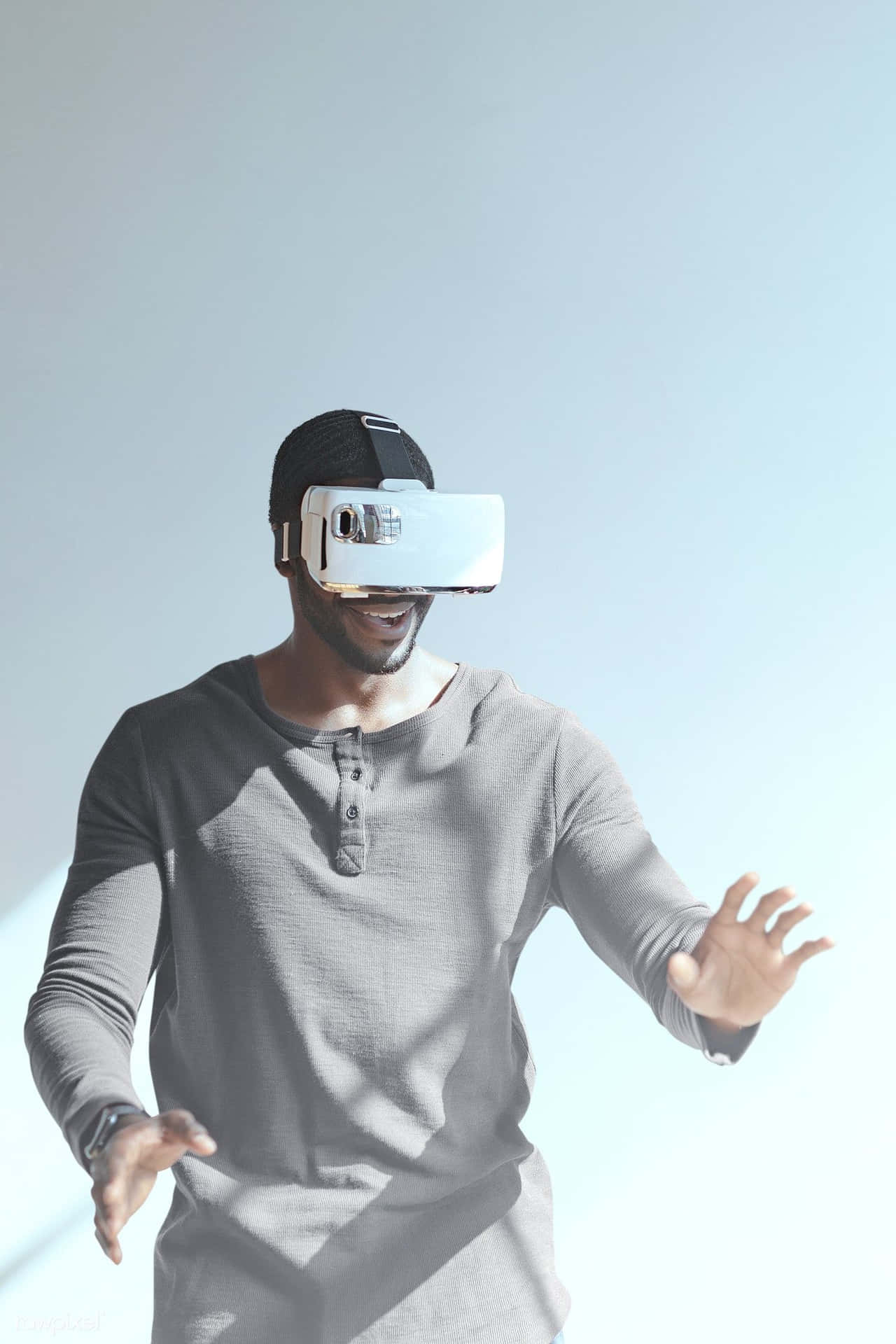 戴VR頭戴式裝置的男子在明亮工作室微笑做手勢。