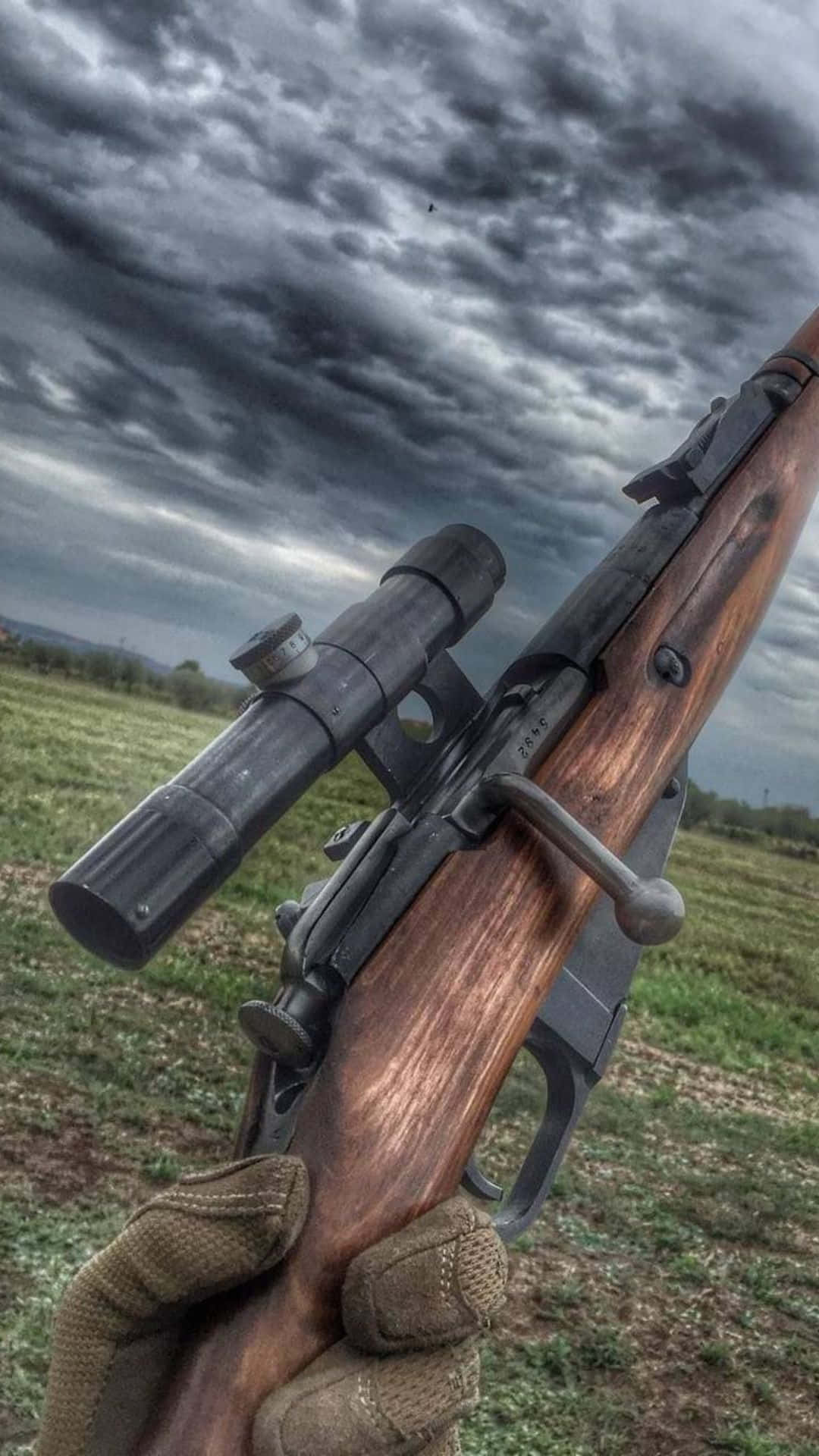 Pubg Guns 桌布 壁紙 — 戴手套的手握著一把帶瞄準鏡的復古栓動步槍，背景是草地上的暴風雨天空。