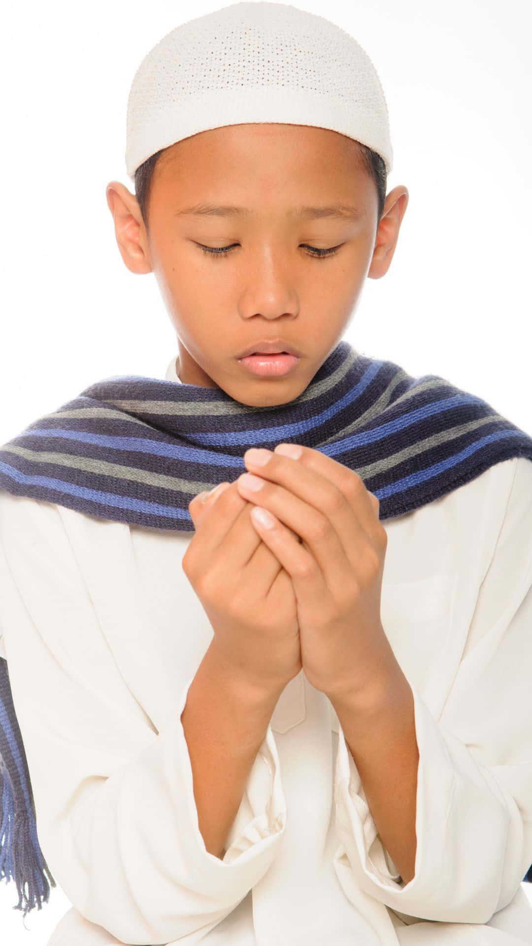 祈禱中的小男孩，雙手合十，閉著眼睛，戴著白色頭巾和藍色圍巾。