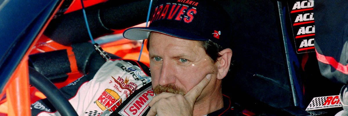 戴爾·艾恩哈特沉思 壁紙 — 一位專注的NASCAR車手戴著亞特蘭大勇士隊帽子，在賽車駕駛艙內將下巴靠在手上。
