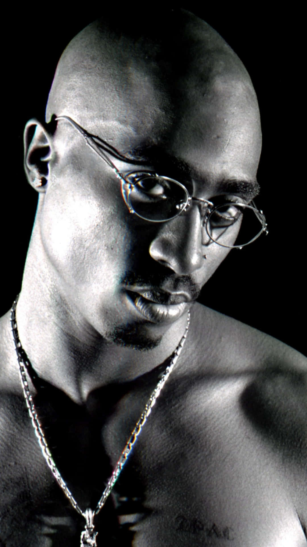 Tupac Shakur 在黑白工作室肖像中戴著眼鏡和鏈條。