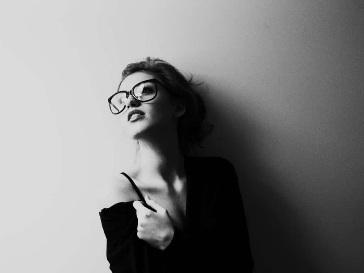 戴眼鏡的女性靠著牆壁的黑白照片。
