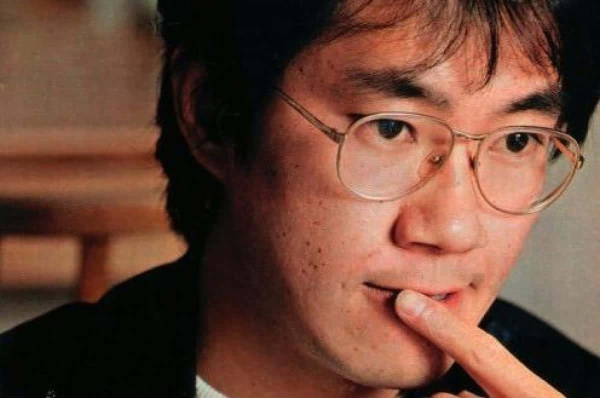 Akira Toriyama 桌布 壁紙 — 戴眼鏡男士的特寫肖像，若有所思地將手指放在唇上。