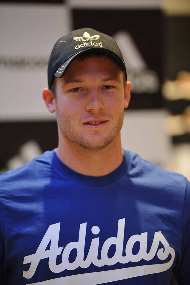 年輕男子戴著黑色Adidas帽子和藍色Adidas T恤。