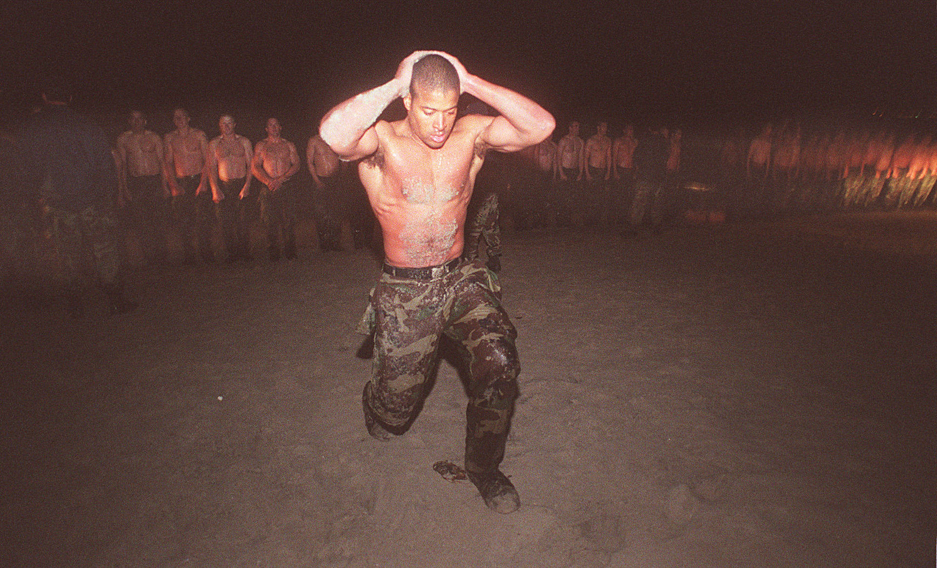 夜間軍事訓練中擦洗頭部的士兵，其他士兵列隊站立。