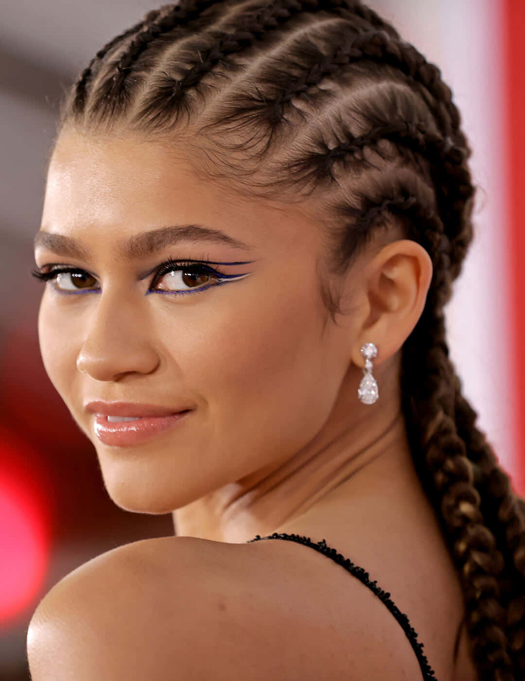 Zendaya 帶著藍色翼形眼線和辮子頭髮，戴著鑽石耳環。