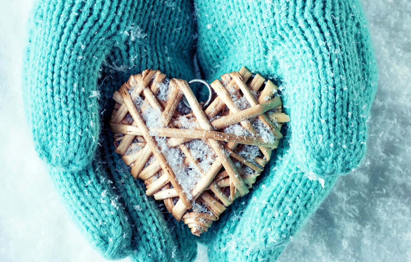Mittens 桌布 壁紙 — 戴著手套的雙手，在霜白的背景上，輕輕捧著一個沾滿雪花的編織心形。