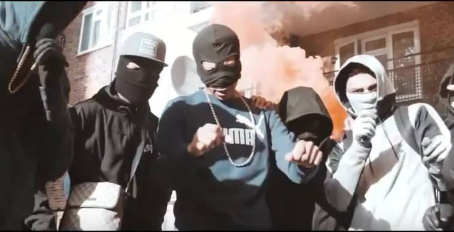 Rappers 桌布 壁紙 — 戴著頭套和巴拉克拉瓦帽的蒙面青年在 gritty 的城市環境中，身後有煙霧，擺出挑釁姿勢。